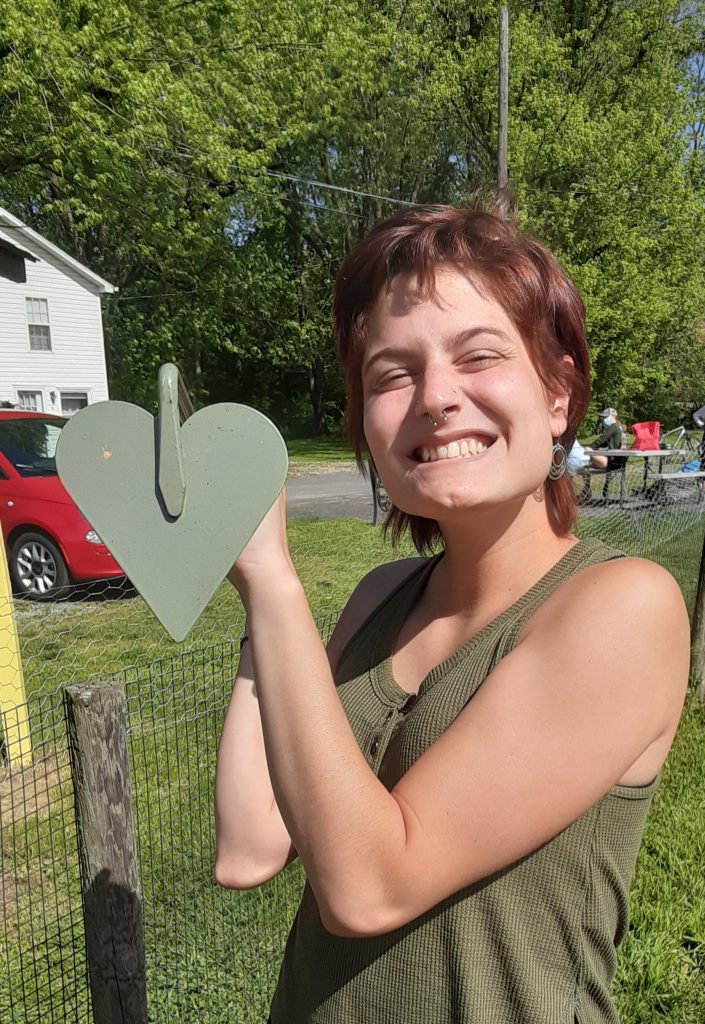 Lauren holds a heart shaped hoe while smiling into the sun. 